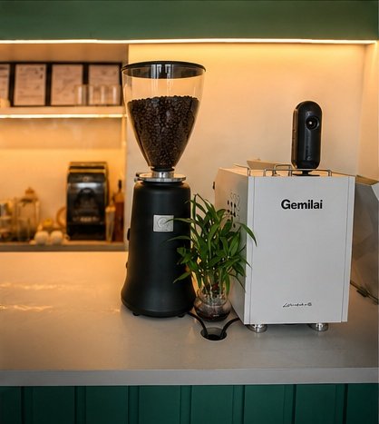 Matte black grinder and white espresso machine on the teal counter