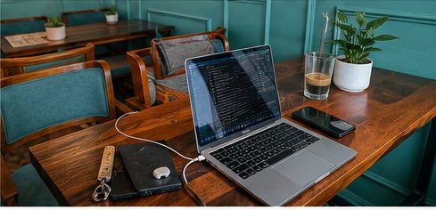 Laptop, phone and a cold coffee on a rosewood table